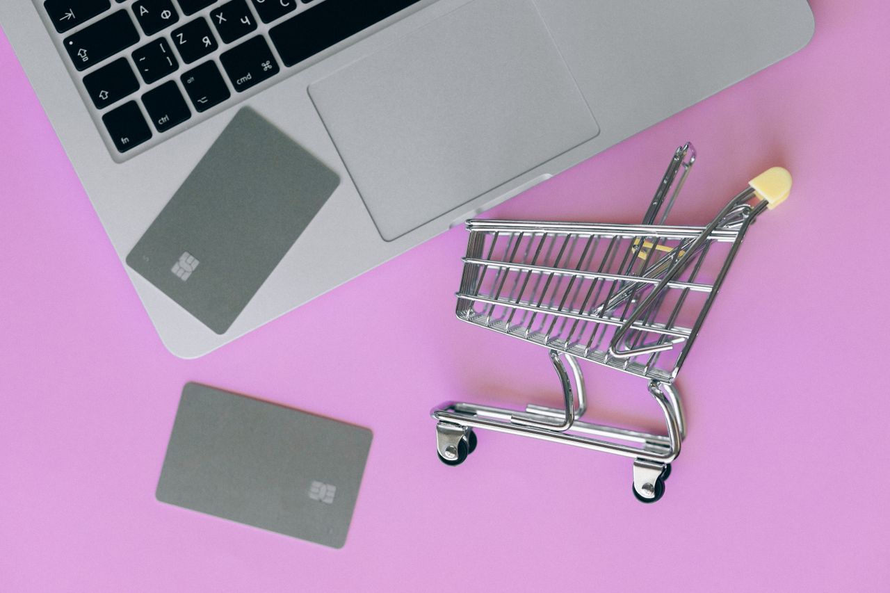 home-hero A minimalist flat lay of a credit card, laptop, and miniature shopping cart.